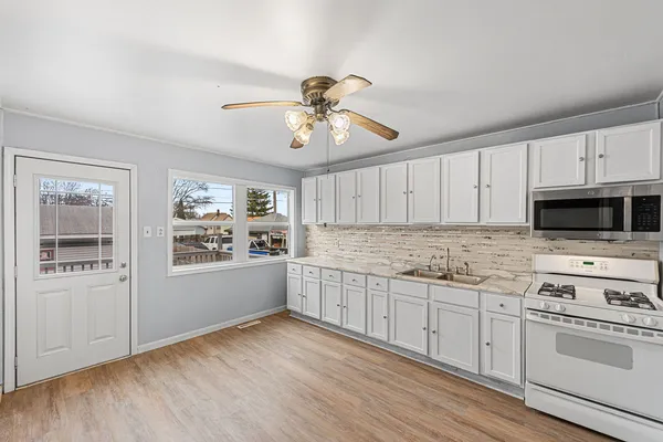 a kitchen with granite countertop a stove a sink and dishwasher with white cabinets