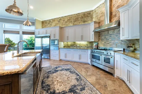a kitchen with stainless steel appliances granite countertop a stove a sink and a white cabinets