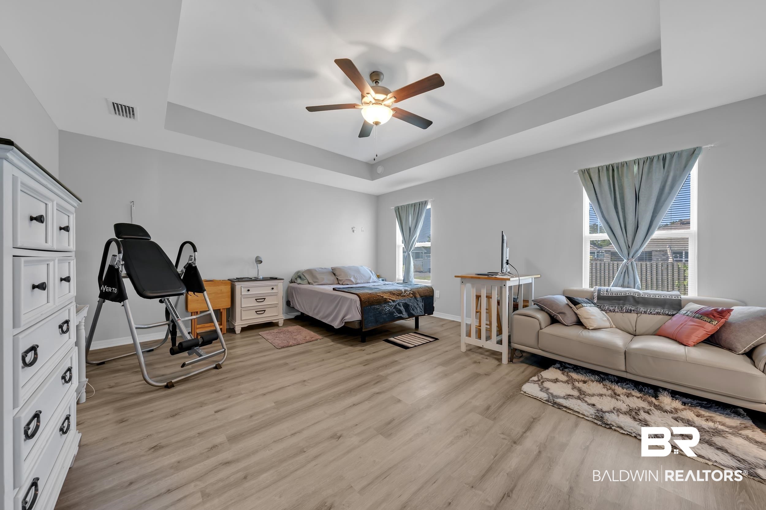 1228 Caper Avenue Foley, AL 36535 - Photo 19 of 54 Spacious bedroom featuring light wood-finish flooring, tray ceiling, and multiple windows providing ample natural light
