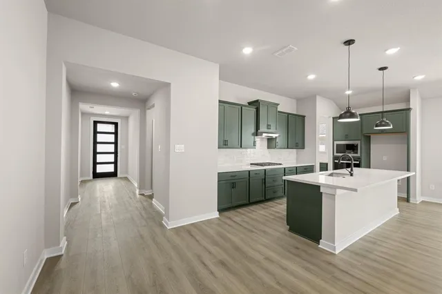 a large kitchen with cabinets wooden floor and stainless steel appliances
