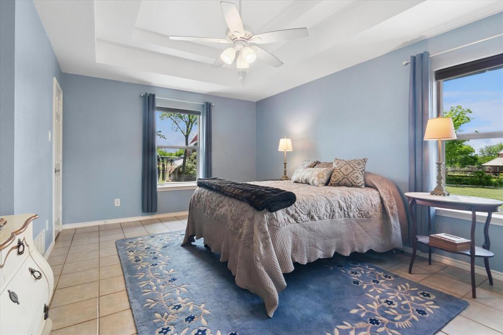 8463 Crestview Road Sanger, TX 76266 - Photo 16 of 36 Bedroom with ceiling fan, a raised ceiling, and light tile patterned floors