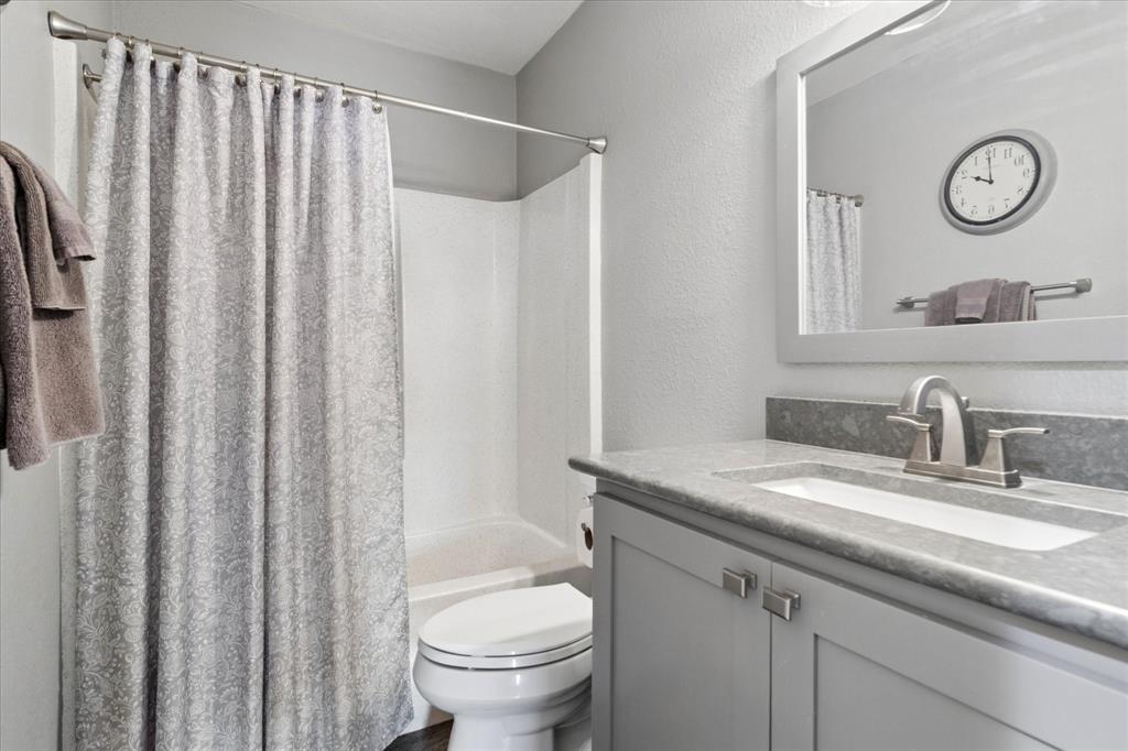8463 Crestview Road Sanger, TX 76266 - Photo 19 of 36 Bathroom featuring a textured wall, vanity, and shower / bath combination with curtain