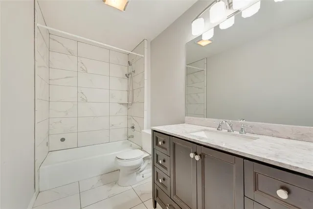 a bathroom with a granite countertop sink a toilet and shower