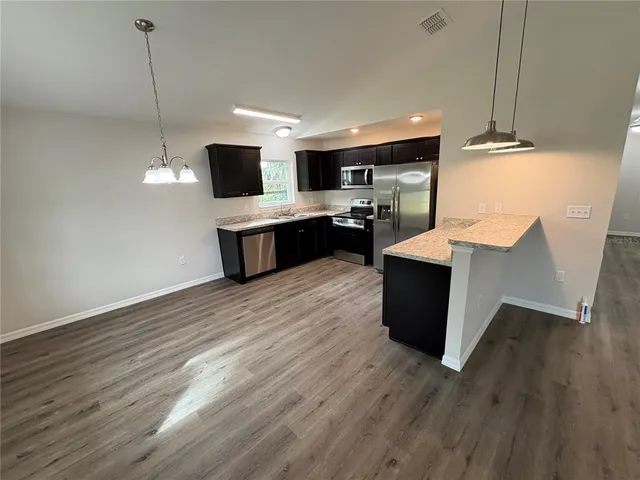 a kitchen with stainless steel appliances kitchen island wooden floors and wooden cabinets