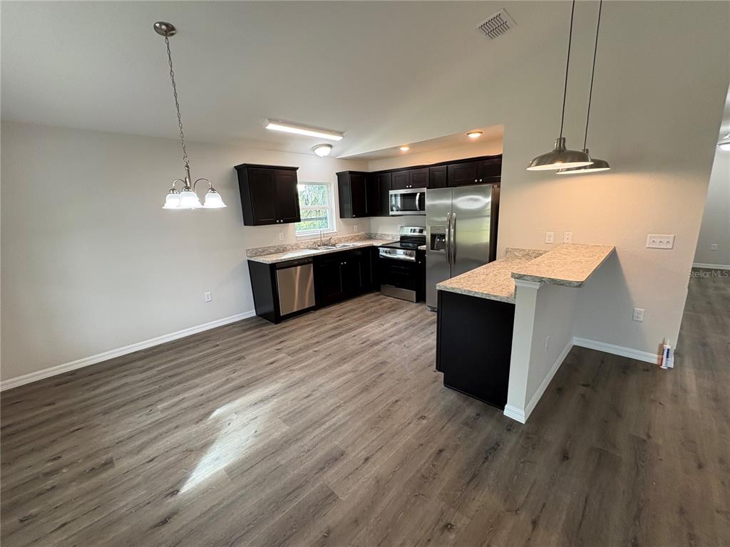 9650 Northwest Gainesville Road Ocala, FL 34482 - Photo 9 of 32 a kitchen with stainless steel appliances kitchen island wooden floors and wooden cabinets
