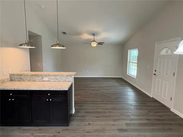 an empty room with wooden floor and ceiling fan