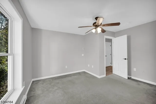 a view of a room with a ceiling fan and carpet