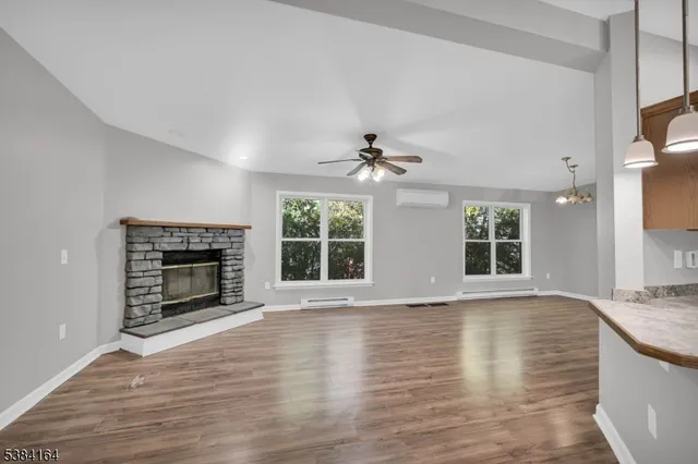 a view of an empty room with wooden floor fireplace and a window
