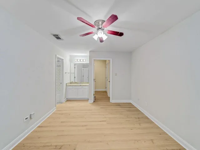 a view of an empty room with window and a ceiling fan
