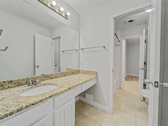 a bathroom with a granite countertop sink and a mirror