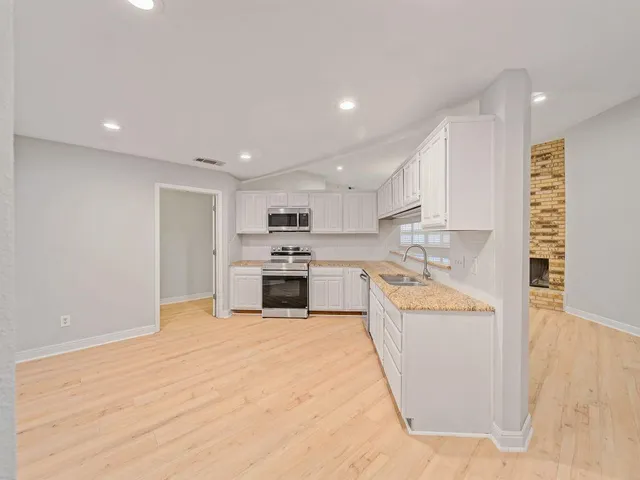 a open kitchen with kitchen island a stove a sink dishwasher and a refrigerator with wooden floor