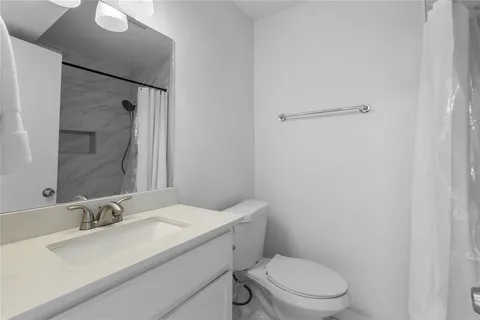 a bathroom with a granite countertop sink mirror vanity and toilet