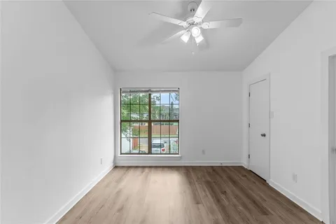 an empty room with wooden floor fan and windows