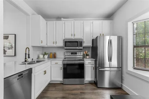 a kitchen with stainless steel appliances a refrigerator a stove a sink and a window