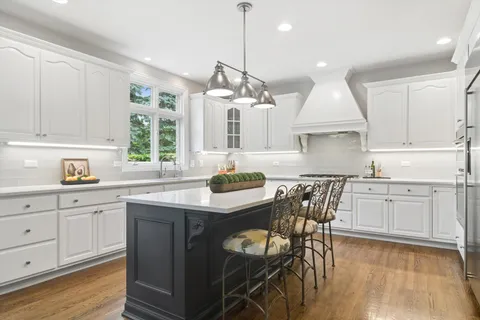 a kitchen with stainless steel appliances granite countertop a sink a stove a dining table and chairs