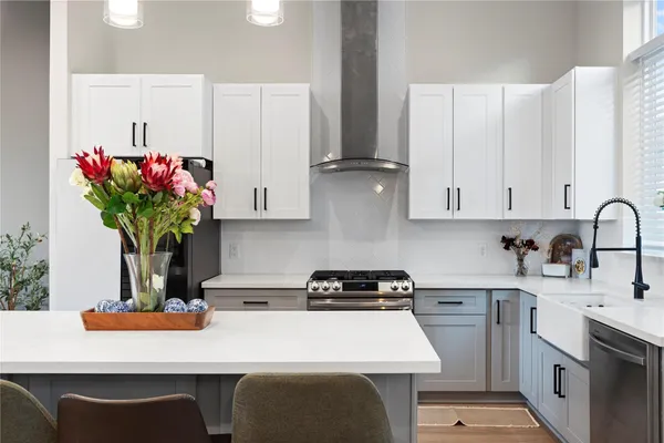 a kitchen with kitchen island granite countertop a sink a stove and white cabinets