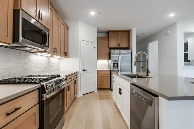 a kitchen with stainless steel appliances granite countertop a stove a sink and a microwave