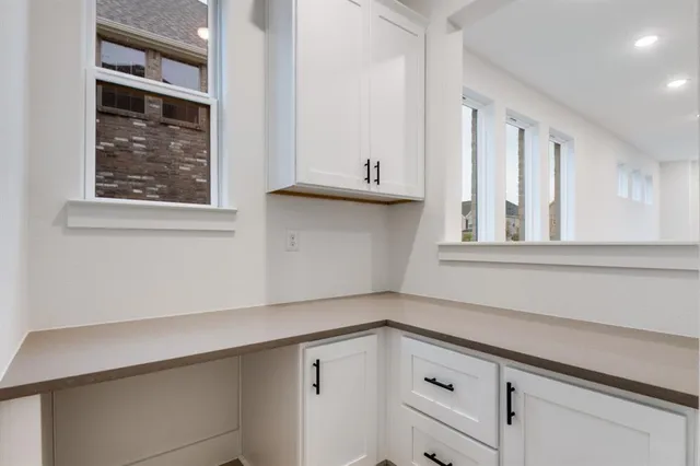 a kitchen with white cabinets and a window