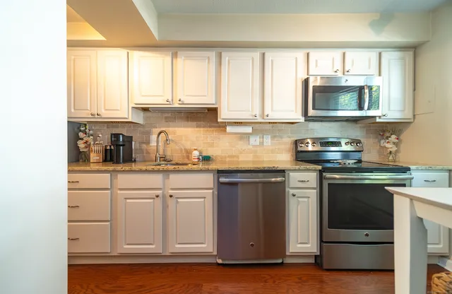 a kitchen with white cabinets and window