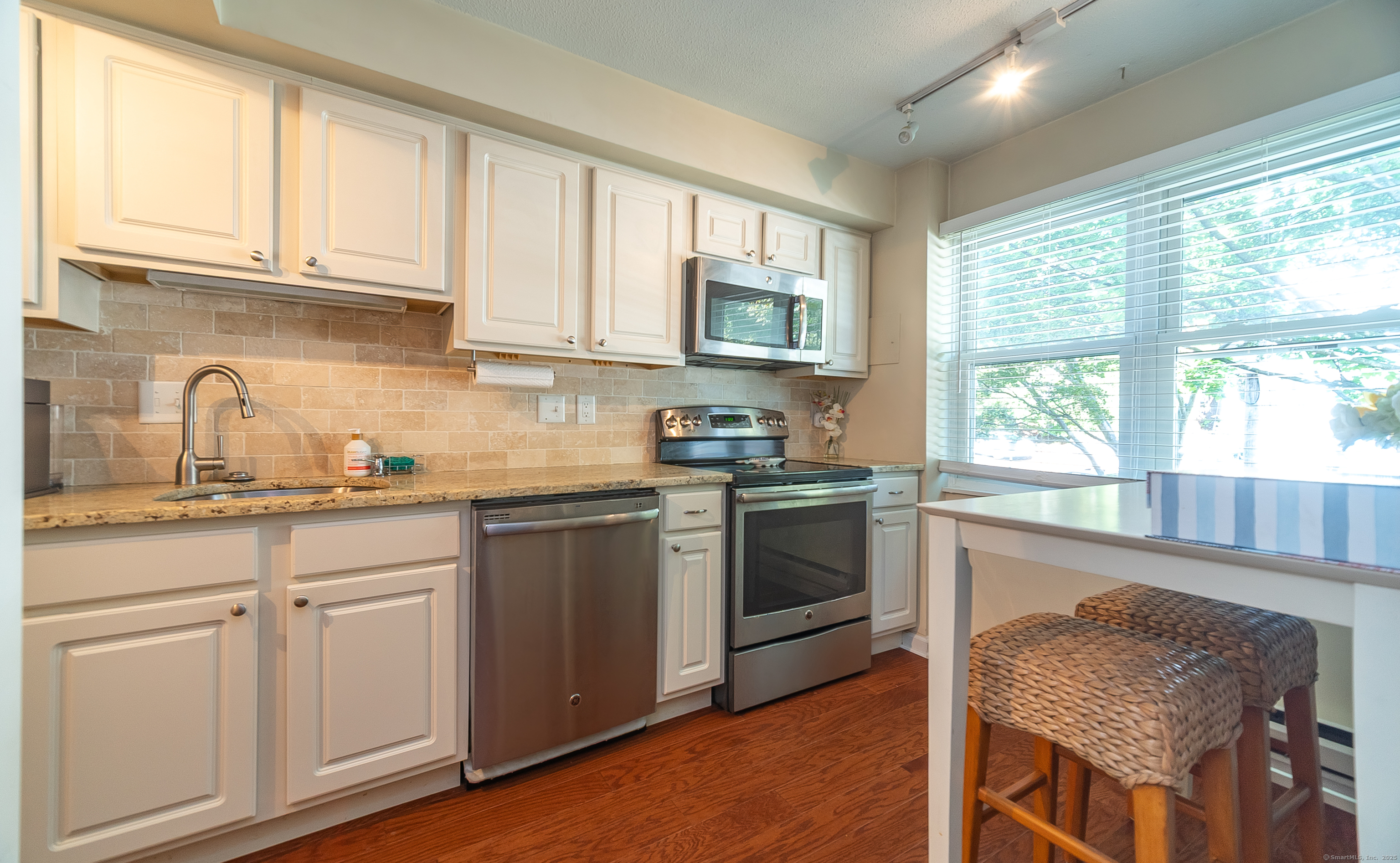 109 Highland Road, Unit 109 Stamford, CT 06901 - Photo 18 of 37 a kitchen with granite countertop wooden cabinets a stove a sink and a window