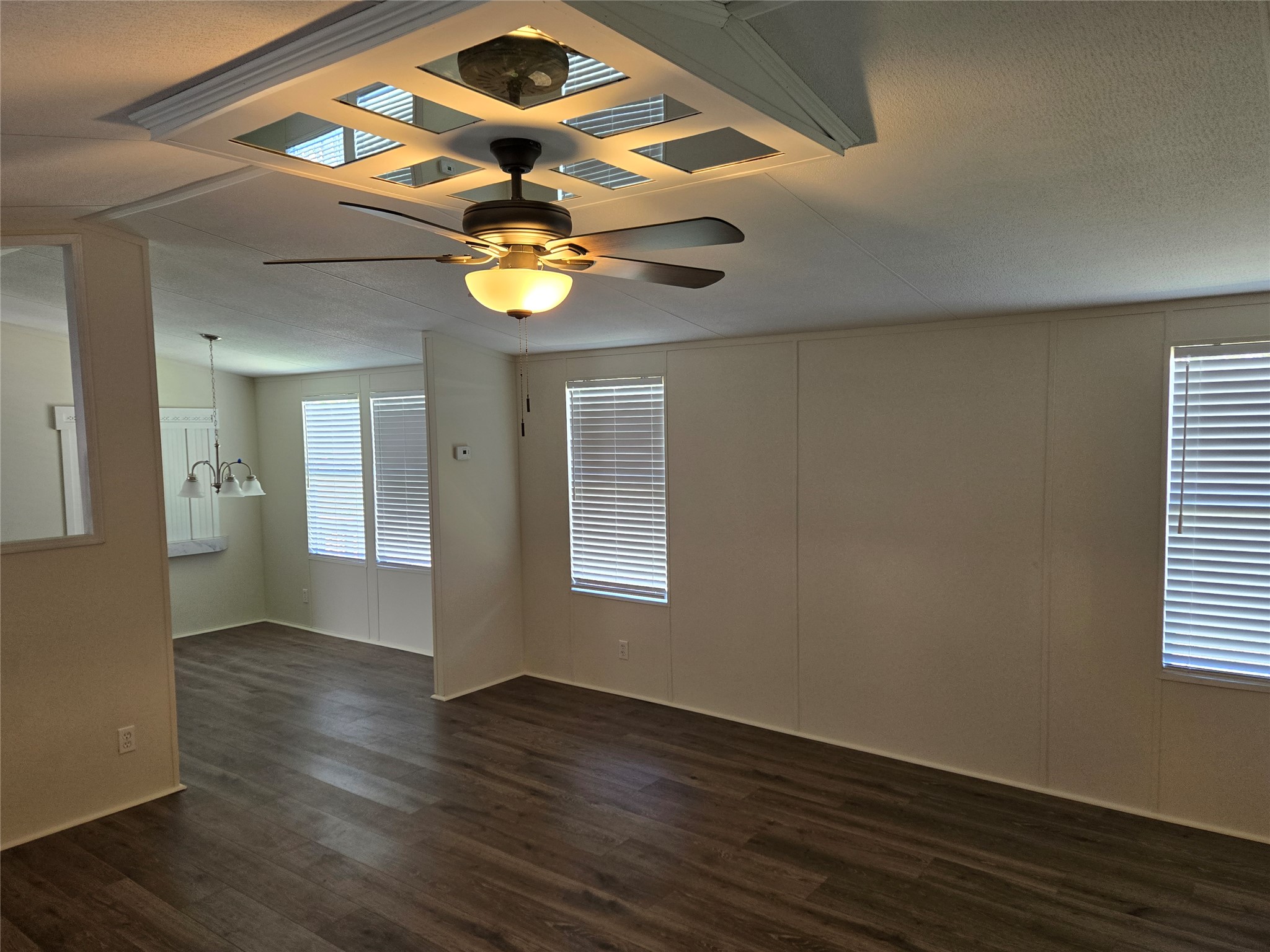 2807 Lone Tree Road Victoria, TX 77901 - Photo 8 of 12 Spacious room with wood-finish flooring, two windows with blinds, and a tray ceiling featuring a ceiling fan with integrated lighting