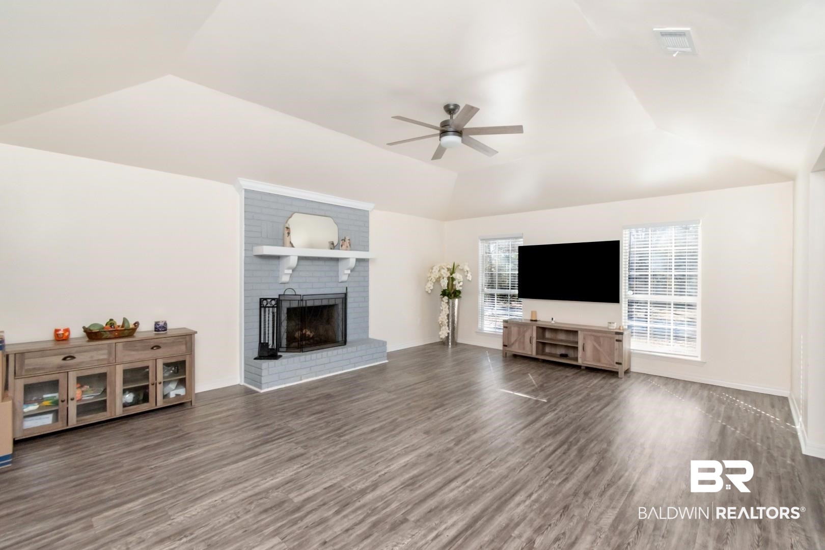 9410 Ashwood Court Mobile, AL 36695 - Photo 6 of 20 Unfurnished living room featuring dark wood finished floors, lofted ceiling, a brick fireplace, and ceiling fan