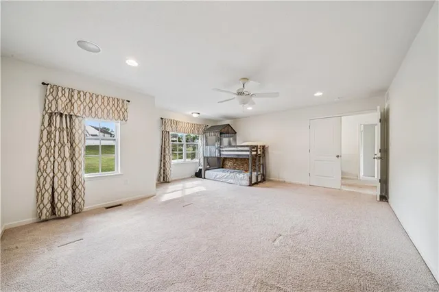 a view of a livingroom with a ceiling fan & windows