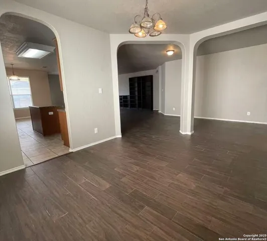 an empty room with wooden floor and chandelier