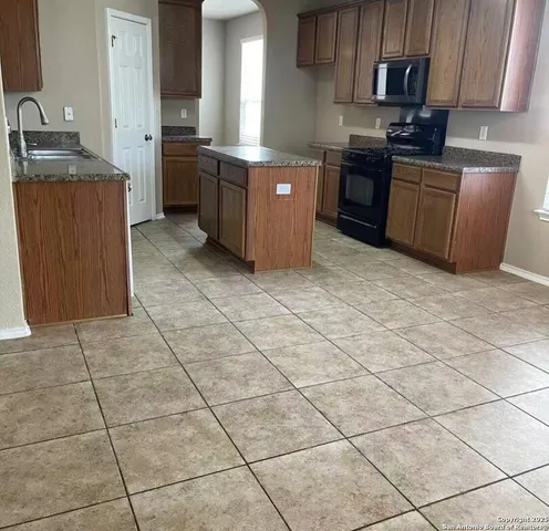 a kitchen with stainless steel appliances granite countertop a stove a sink a microwave and a refrigerator