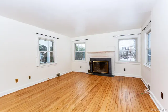 a view of empty room with wooden floor and fireplace