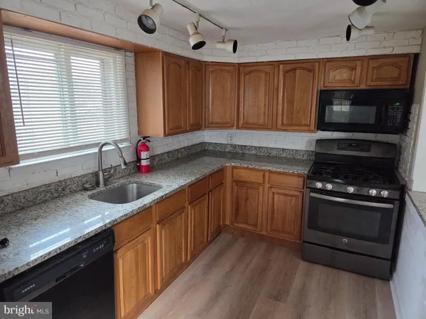 a kitchen with stainless steel appliances wooden cabinets a stove a sink and a microwave