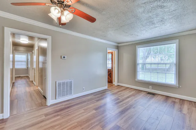 a view of an empty room with wooden floor and a window