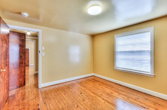 a view of an empty room with wooden floor and a window