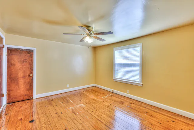 a view of an empty room with a window and wooden floor