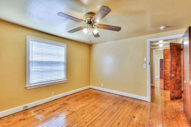 a view of an empty room with wooden floor and a window