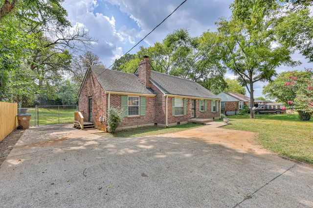 a view of a house with a yard and large trees