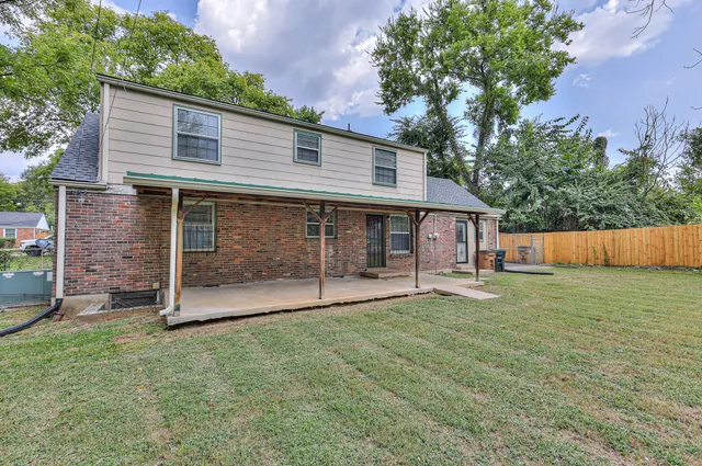 a view of a house with a yard and a large tree