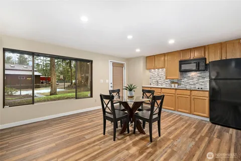 a kitchen with stainless steel appliances granite countertop a stove a refrigerator a sink with a dining table and chairs with wooden floor
