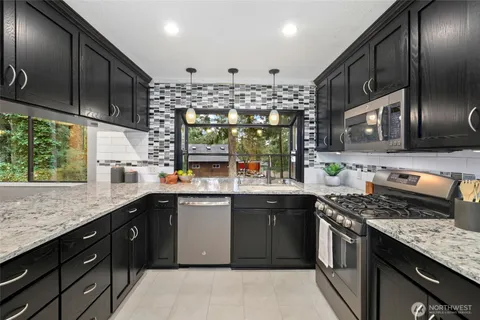 a kitchen with stainless steel appliances granite countertop a sink a stove and a wooden floors