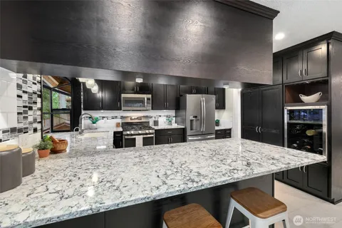 a kitchen with stainless steel appliances kitchen island granite countertop a refrigerator a stove top oven and a sink with wooden floor