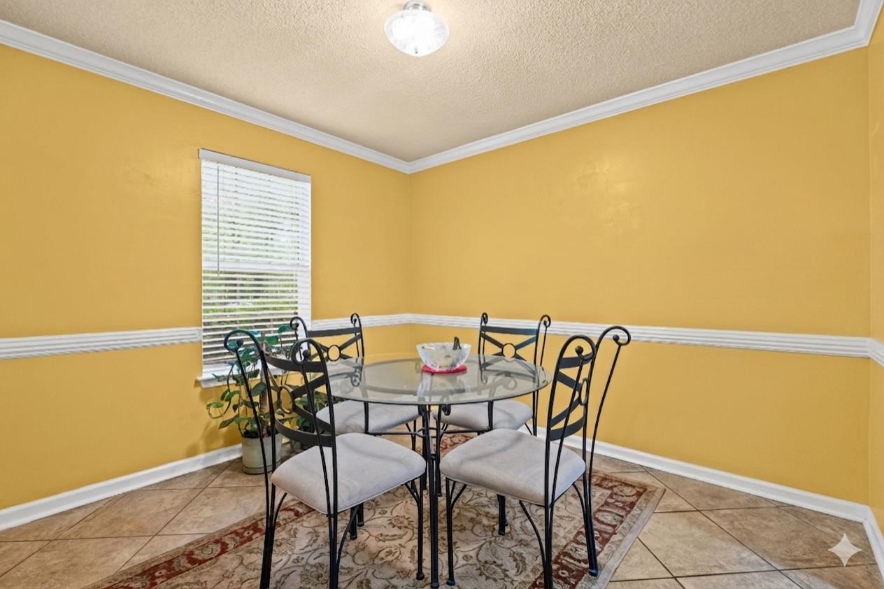 7788 Reese Road Memphis, TN 38133 - Photo 9 of 23 Dining area featuring tile flooring, a single window with blinds, decorative chair rail molding, crown molding, and a flush-mount ceiling light fixture