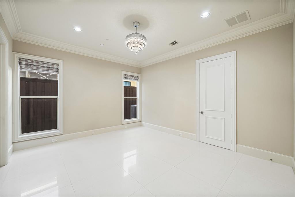 5821 Northaven Road Dallas, TX 75230 - Photo 21 of 40 Spacious room featuring white tile flooring, crown molding, a two-panel interior door, and a tiered crystal chandelier