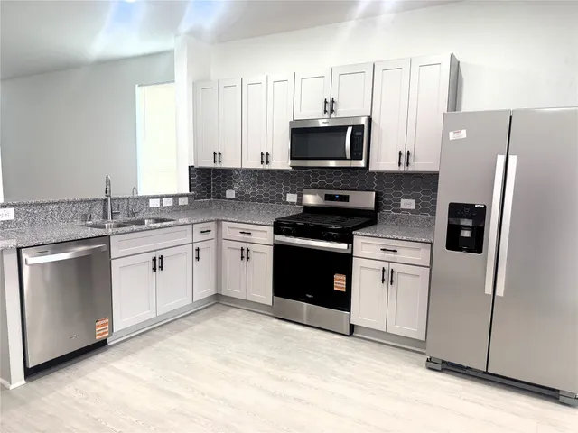 a kitchen with white cabinets and white appliances