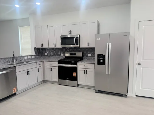 a kitchen with stainless steel appliances white cabinets and a refrigerator