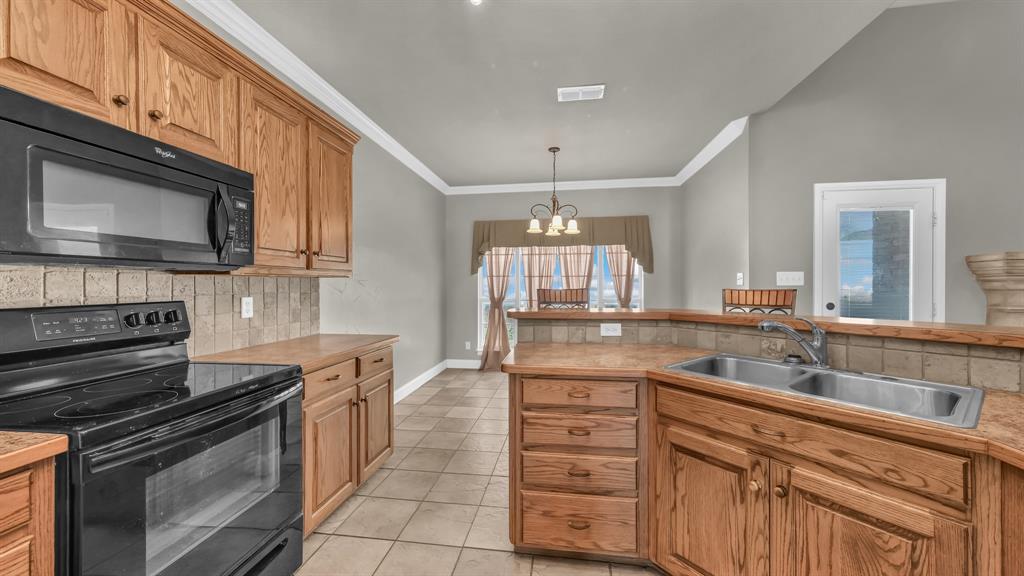 1106 Owl Street Decatur, TX 76234 - Photo 21 of 40 a kitchen with stainless steel appliances granite countertop a sink dishwasher stove and oven with wooden cabinets