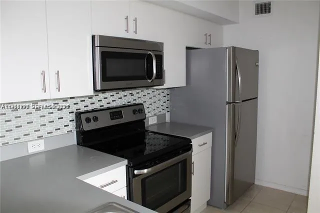 a kitchen with granite countertop a stove microwave and refrigerator
