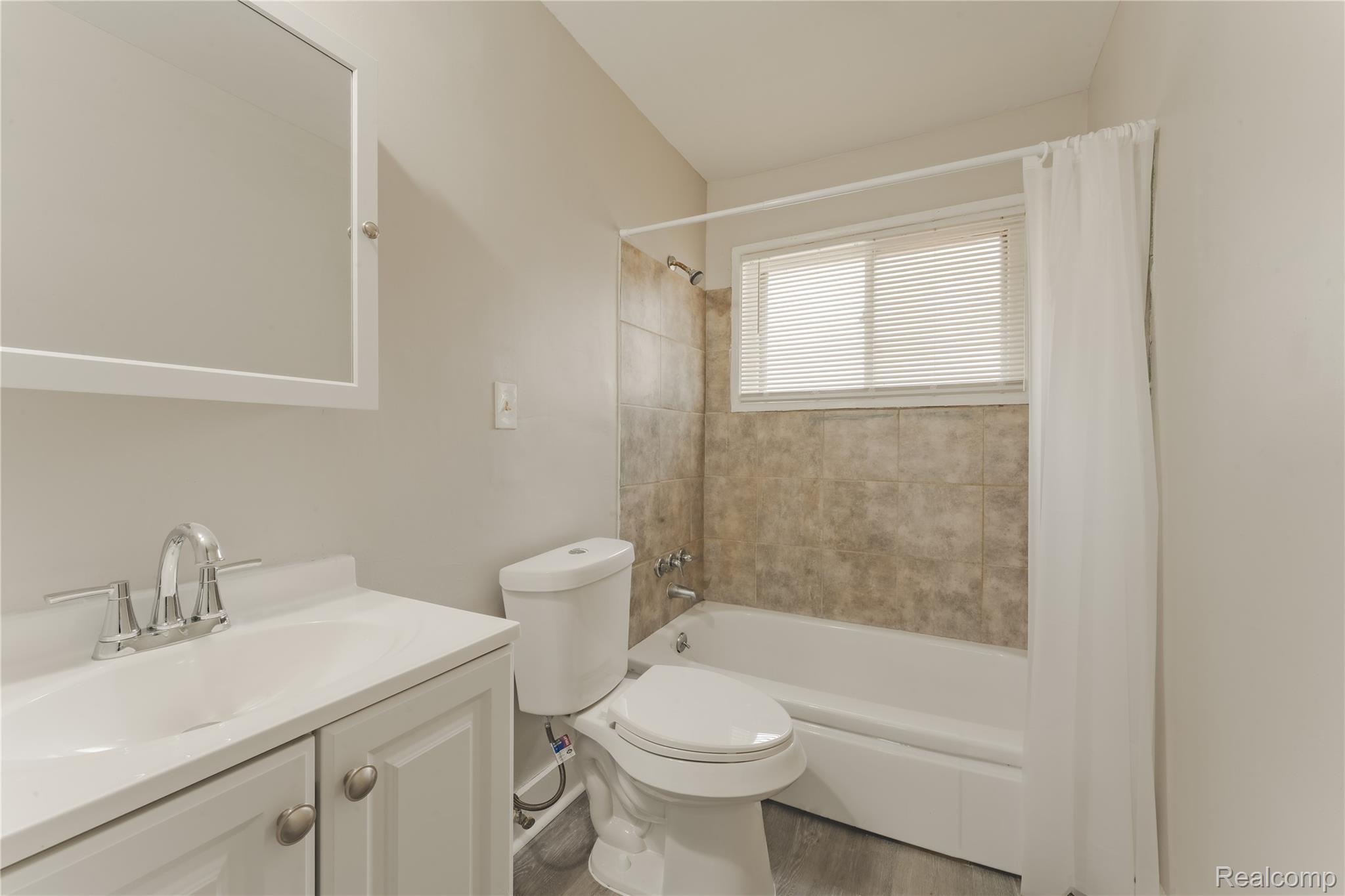 93 West Princeton Avenue Pontiac, MI 48340 - Photo 14 of 31 Bathroom featuring a white vanity with integrated sink, chrome faucet, white medicine cabinet, and a bathtub with tiled surround