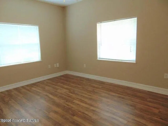an empty room with wooden floor and a window