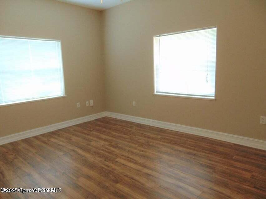 2087 Hidden Grove Lane, Unit 105B Merritt Island, FL 32953 - Photo 18 of 22 an empty room with wooden floor and a window