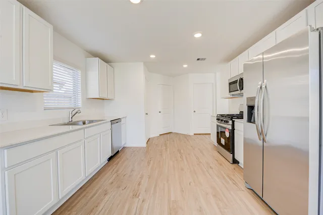 a kitchen with white cabinets and stainless steel appliances